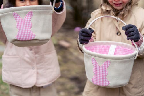 Crop children in warm clothes showing toys buckets