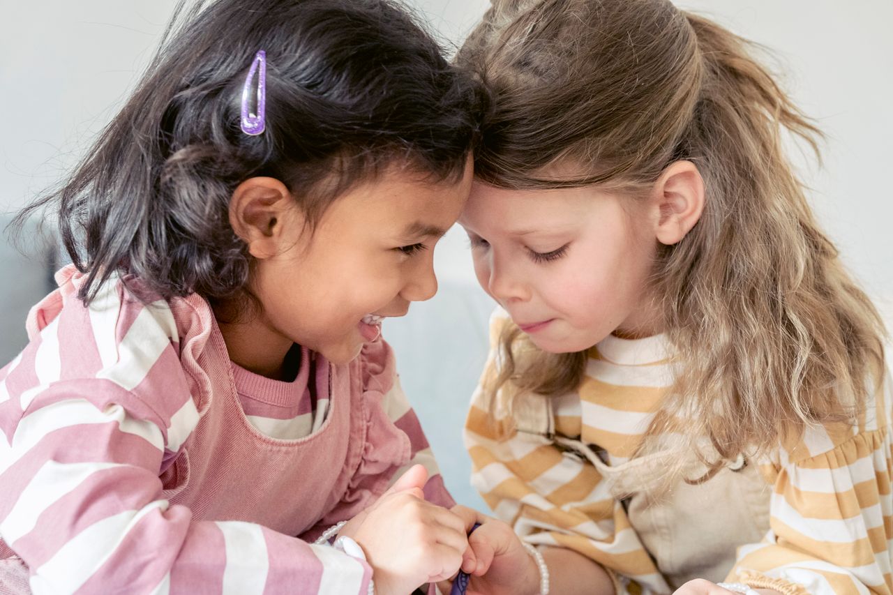 cute multiethnic preschooler girls making gesture with fingers as sign