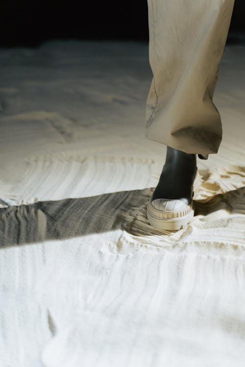 Person in White Shoes Standing on Gray Sand