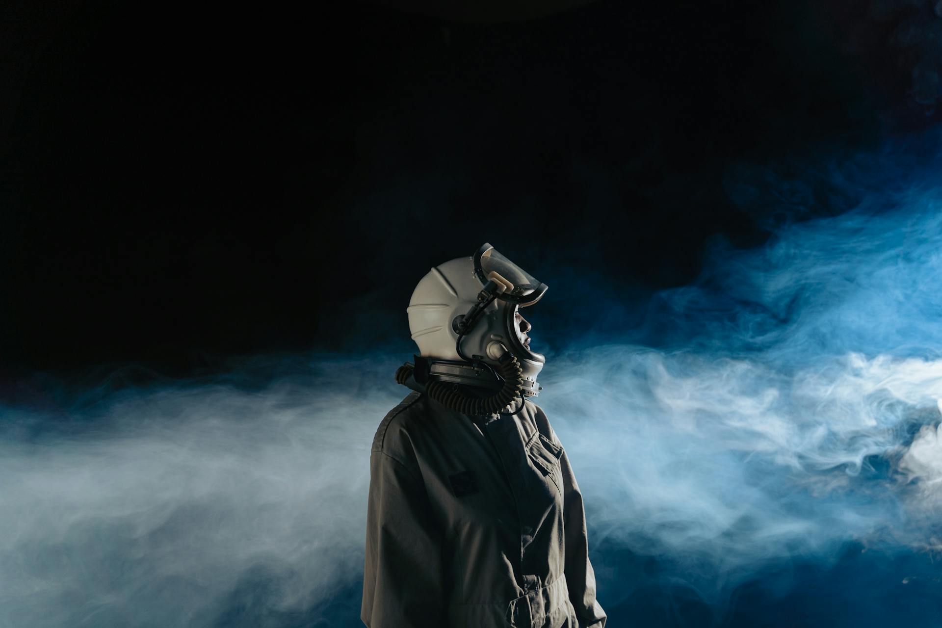 Person in Gray Space Suit with Blue and White Smoke on Background