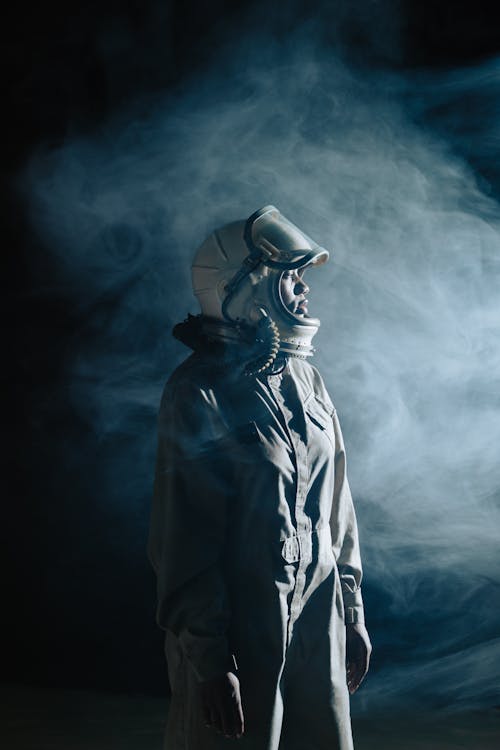 Free Person in Gray Space Suit and Helmet Standing with Smoke on Background Stock Photo