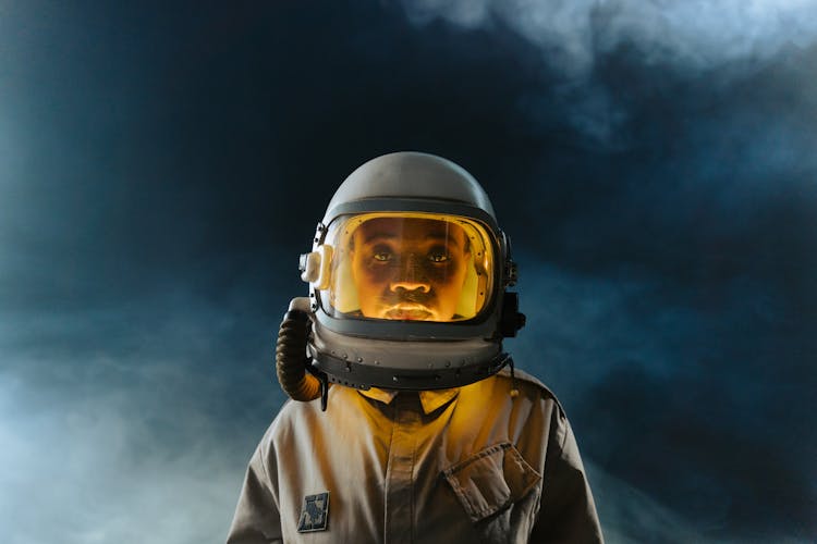 Man In White Helmet With Orange Light And Brown Space Suit  In Outerspace