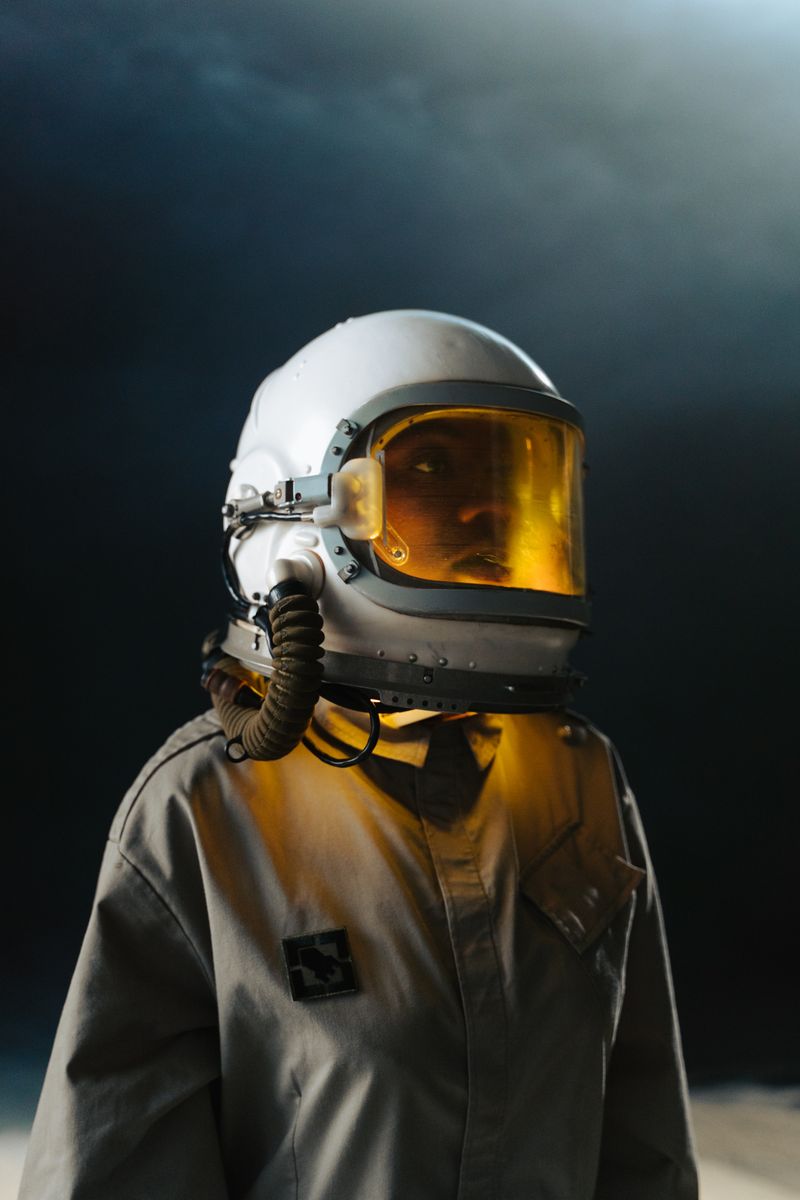 Figure in a vintage pressure suit lit by an amber visor glow — photo by cottonbro studio on Pexels