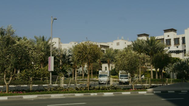 View of modern buildings amidst tropical landscaping with clear skies.