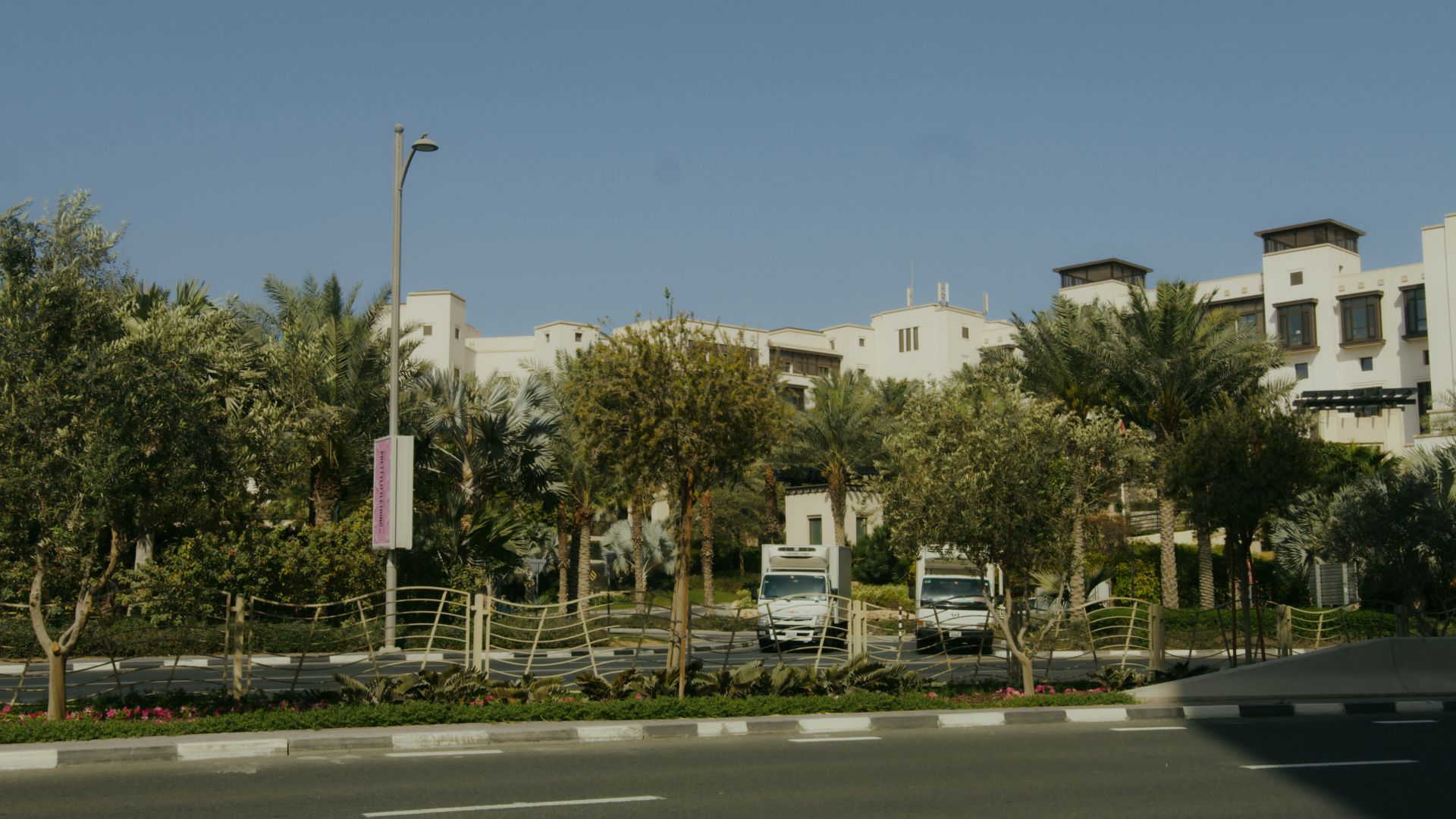 View of modern buildings amidst tropical landscaping with clear skies.