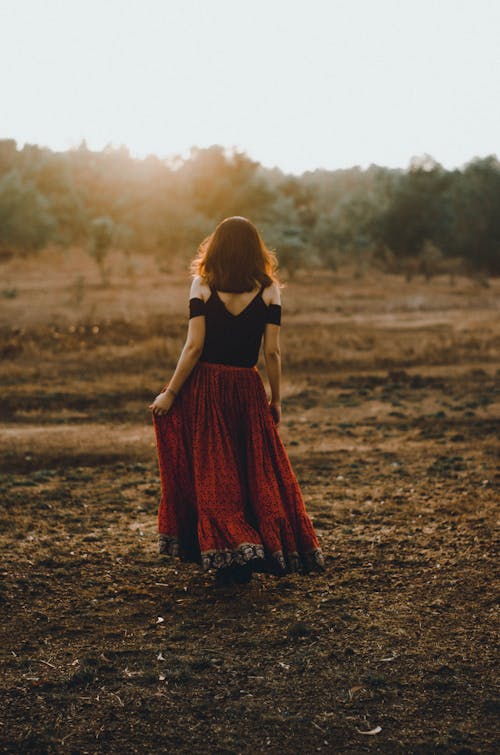 Woman in Black and Red Dress Standing on Dirt Ground