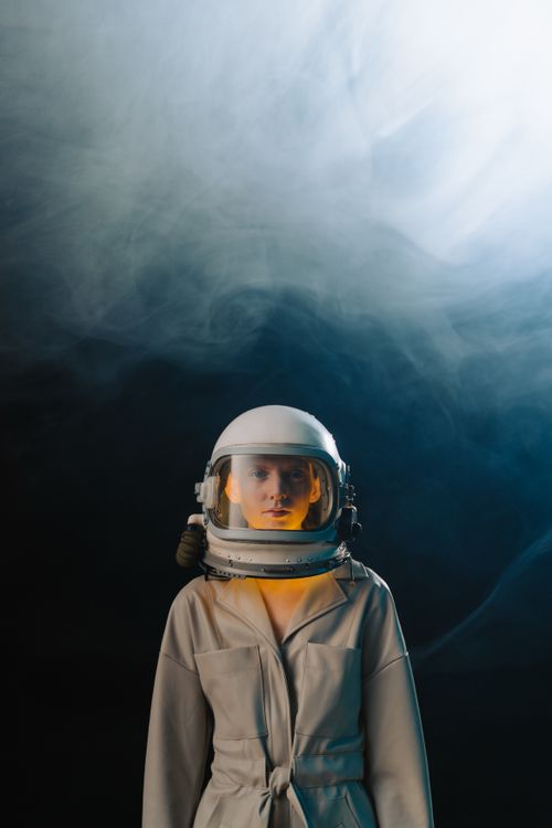 Free A captivating portrait of a woman wearing a spacesuit with room for text in a moody setting. Stock Photo