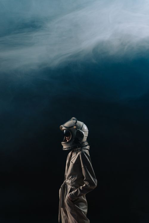 Free Person in astronaut suit and helmet against a cloudy sky backdrop. Stock Photo