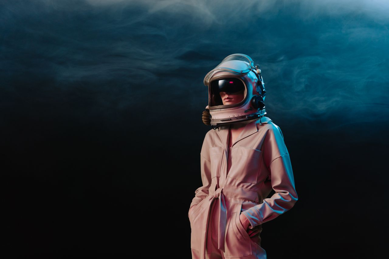 stylish woman in astronaut suit standing in a dramatic studio setting