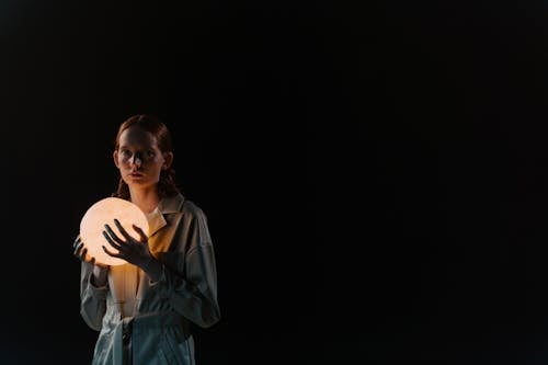 A Woman Holding a Light Sphere on Black Background
