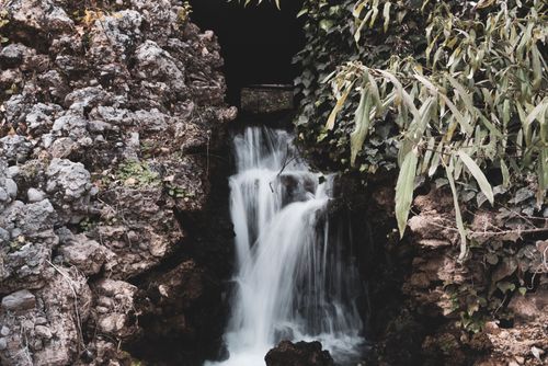 Free A tranquil waterfall cascades over rocky terrain surrounded by lush greenery. Stock Photo