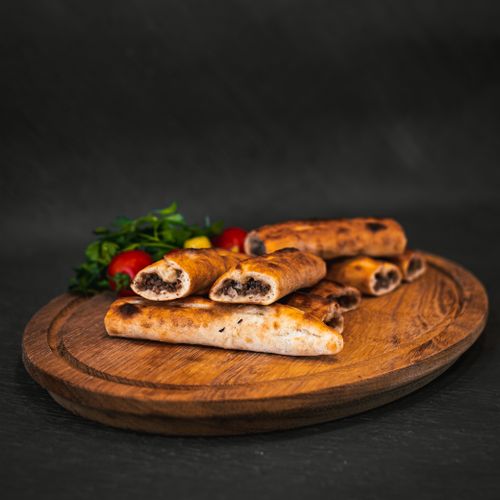 Free Mouthwatering Turkish börek served on a wooden plate with fresh greens and tomatoes. Stock Photo