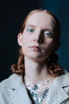 Artistic portrait of a woman with blue eyes and glittery makeup creating a moody, enigmatic atmosphere.