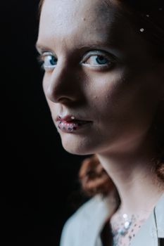 Close-up portrait of a person with glitter makeup and blue eyes, showcasing a moody and artistic style.