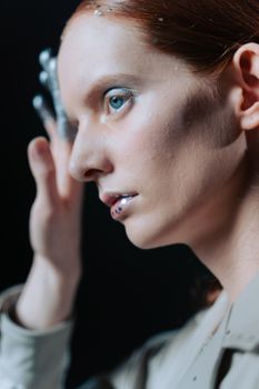 Close-up portrait of a woman with blue eyes and glitter makeup, showcasing artistic beauty.