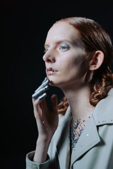 Creative studio portrait of a woman with glitter and a silver-painted hand, showcasing modern artistry.