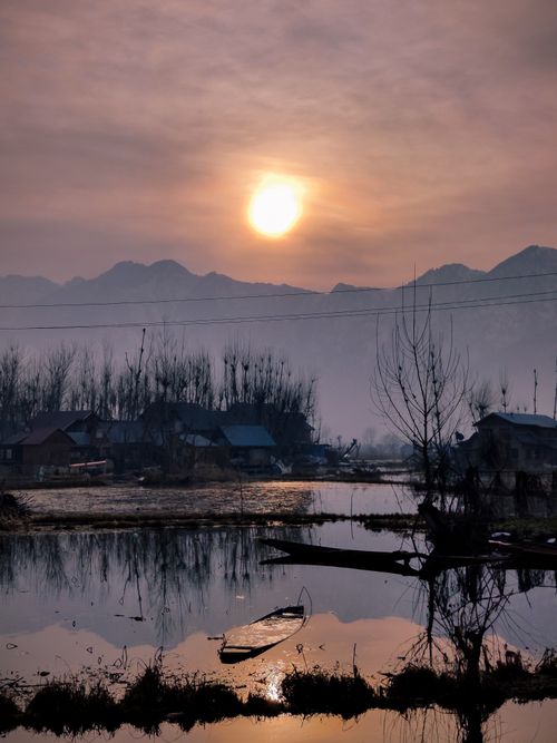 Free A tranquil village by the lake at sunset, featuring a reflection of the scenery in the water. Stock Photo