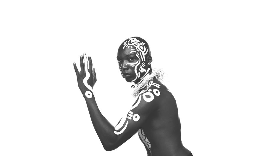 Creative monochromatic portrait of a man with intricate tribal body art, photographed in Kinshasa.