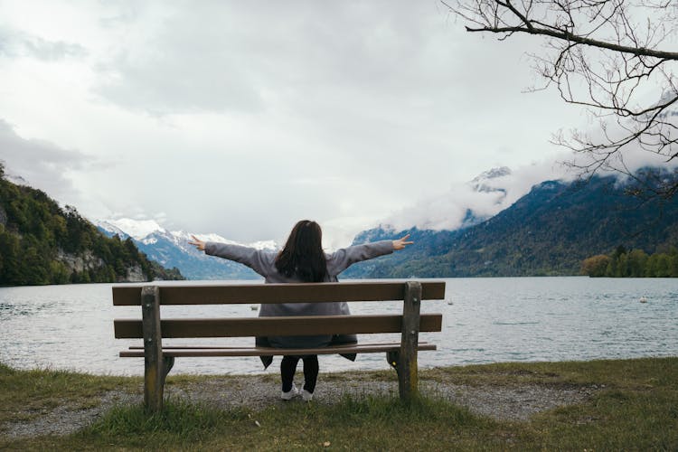 Woman Sitting On Bench By Lake