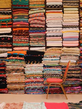 Colorful stacked fabrics with a red chair in a Dubai textile shop.