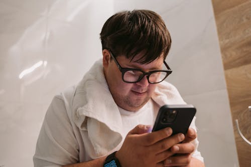 Close-Up Shot of a Man with Eyeglasses in White Shirt Using a Mobile Phone