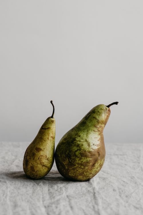 Free Close-up of two fresh green pears on a textured linen surface with a minimal white background. Stock Photo
