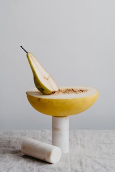 Elegant still life of a sliced melon and pear on marble, showcasing minimalist composition and textures.