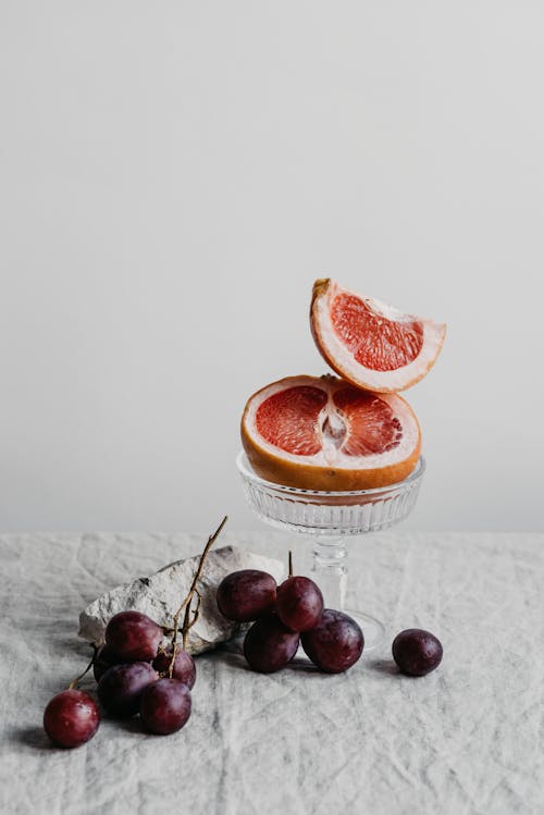 Photo of a Sliced Grapefruit Near Grapes