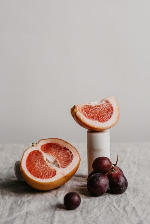 Free Elegant still life featuring grapefruit and grapes with a minimalist aesthetic on a neutral background. Stock Photo