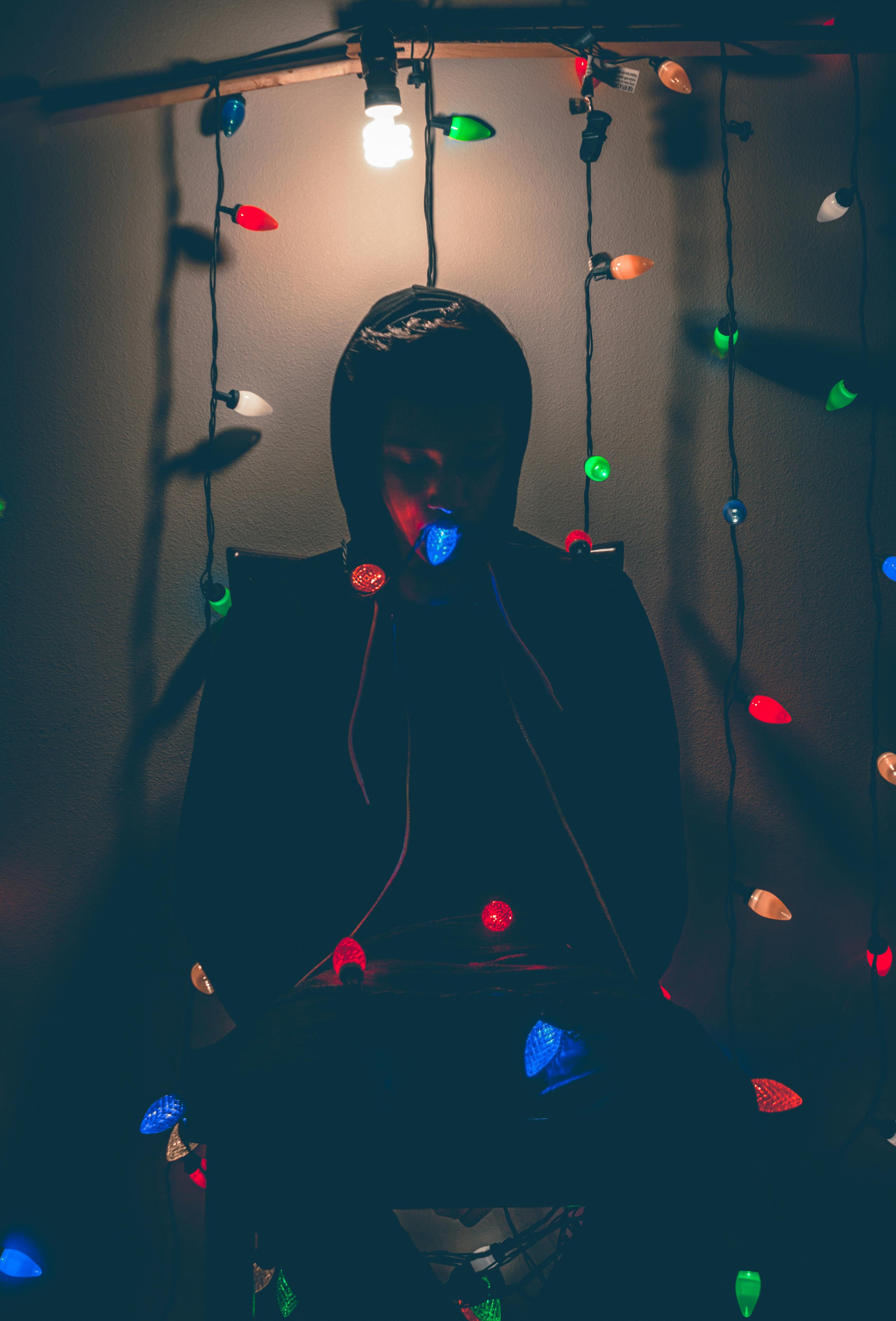 Man Sitting on Chair With Multicolored String Lights · Free Stock Photo