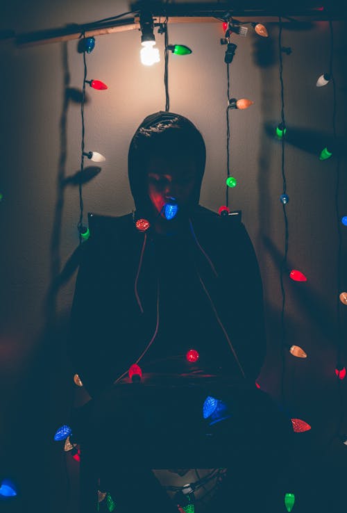 Free Man Sitting on Chair With Multi-colored String Lights Stock Photo