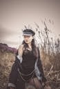 Woman in Black Jacket with Black Hat Standing on Grass Field