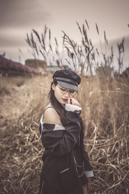 Free Woman in Black Jacket and Black Cap Standing on Brown Grass Field Stock Photo