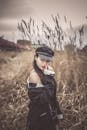 Woman in Black Jacket and Black Cap Standing on Brown Grass Field
