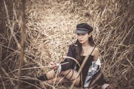 Woman with a Black Cap Sitting on Dried Grass