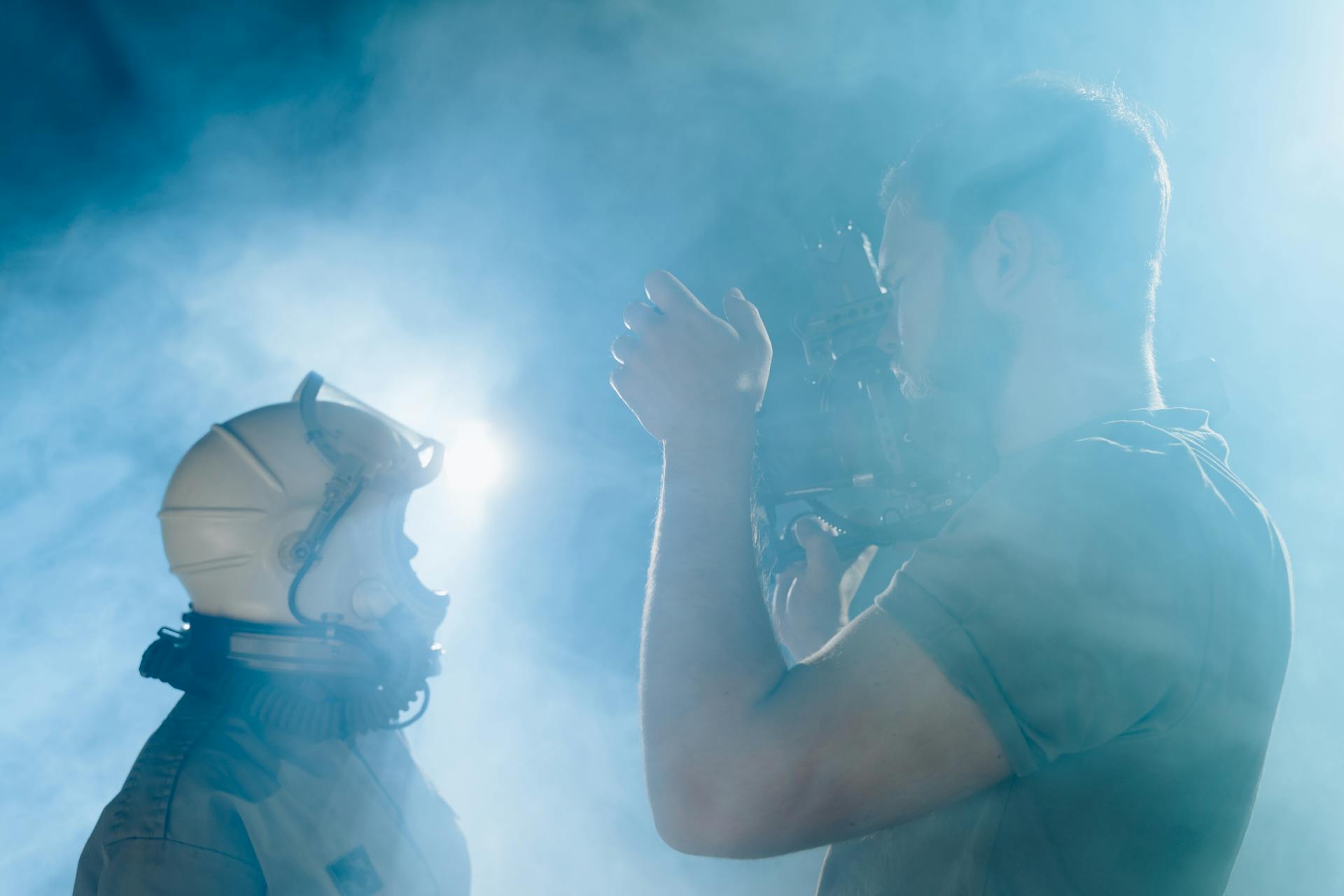 Person in Space Suit Beside a Man Filming