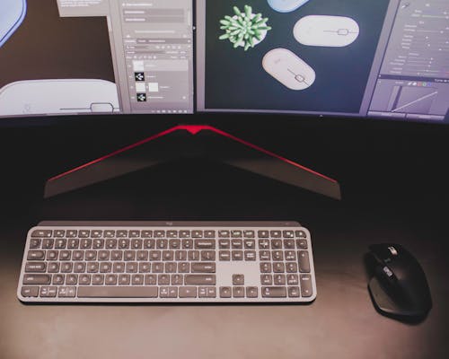 Close-Up Shot of Wireless Keyboard and Mouse near Computer Monitor