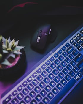 Stylish dark-themed workspace featuring an illuminated keyboard and a black mouse, perfect for tech enthusiasts.