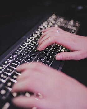 Hands typing on a backlit keyboard, illustrating remote work or online communication.