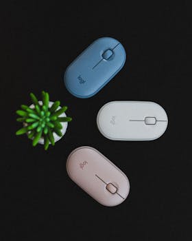 Three wireless computer mice placed on black background with a green plant.