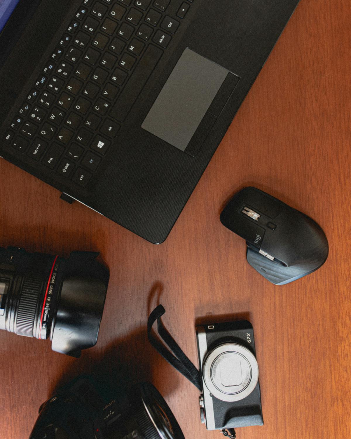 Contemporary laptop and photo camera with lens on table · Free Stock Photo