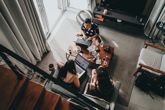 Three people working together in a cozy home setting using laptops.
