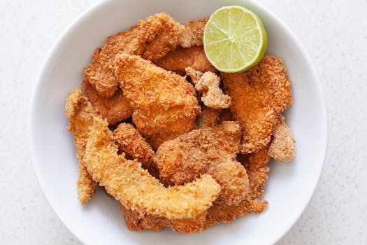 Delicious crispy fried chicken served on a white plate with a fresh lime wedge.