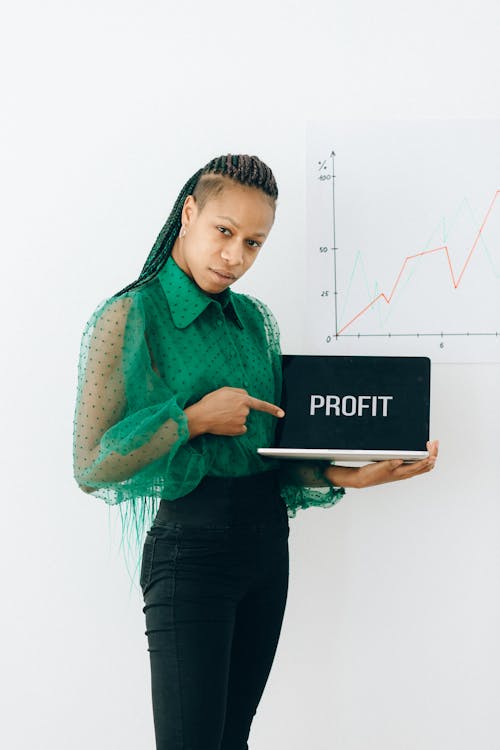 Woman in a Green Top Pointing at a Laptop