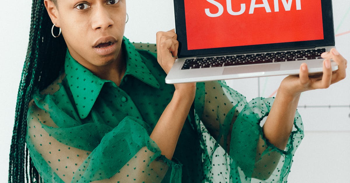Photo by Nataliya Vaitkevich A shocked woman holding a laptop displaying a scam alert in a bright room.