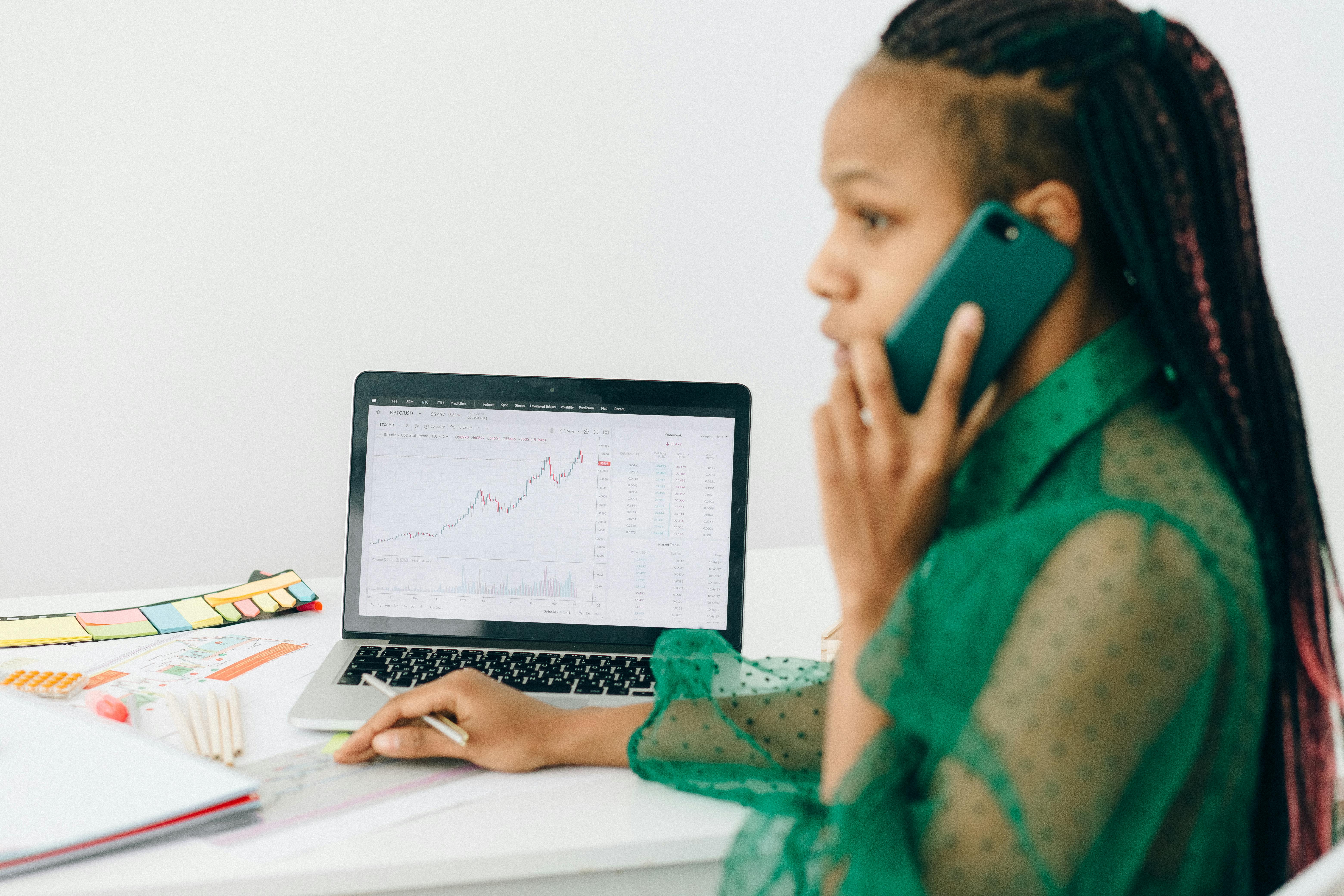 woman in talking on the phone near a laptop