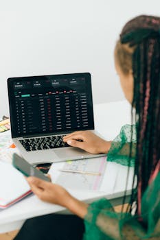A woman analyzing financial data on a laptop, using technology for business insights.