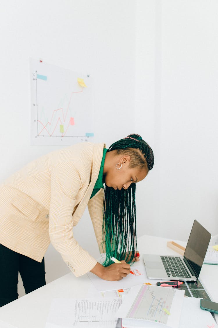 A Woman Writing Near A Laptop