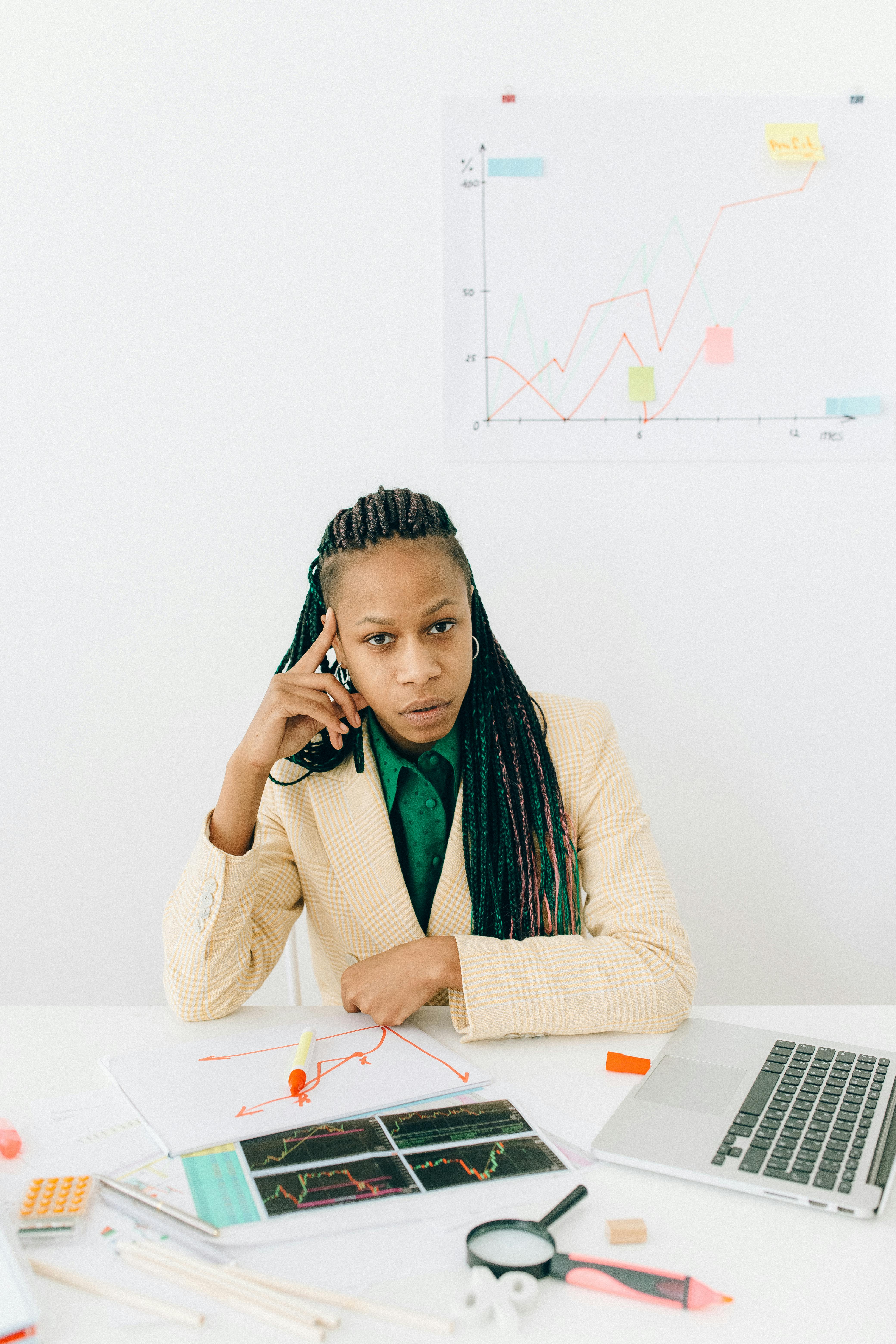 Professional woman analyzing financial graphs and data at an office desk, showcasing business expertise.