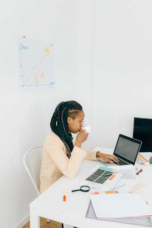 Woman drinking Beverage while working on Laptop 